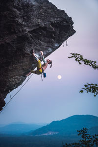 Low angle view of people on rock against sky