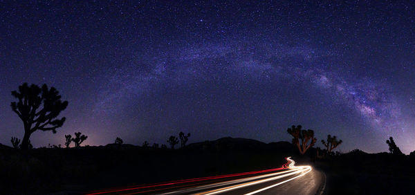 Light trails on road against sky at night