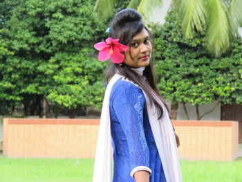 Portrait of smiling young woman wearing flower in park