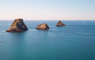 Rocks in sea against clear sky