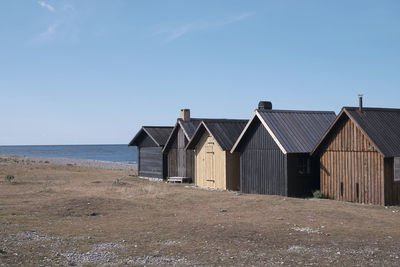 Houses on beach by sea against clear sky