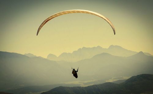 Person paragliding over mountain landscape