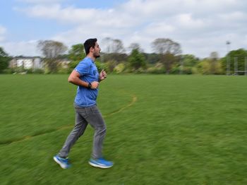 Side view of man jogging on field at park
