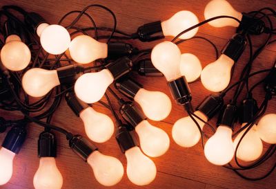 High angle view of illuminated light bulbs on wooden table