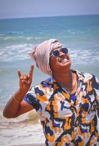 Young woman wearing sunglasses on beach against sky