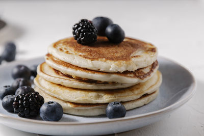 Stack of pancakes with berries on top on a white surface