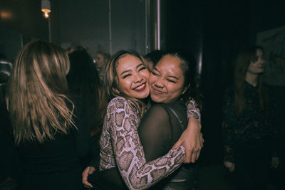 Cheerful young women embracing each other while enjoying at nightclub