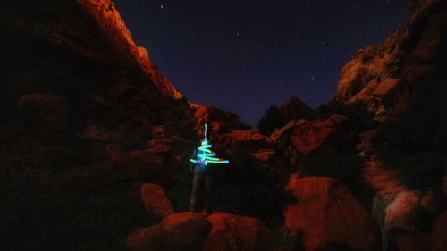 Illuminated light on rock against sky at night