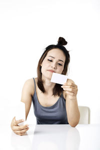Portrait of young woman using phone against white background