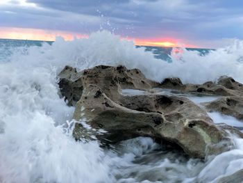 Panoramic view of sea waves splashing on rocks against sky