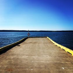 Pier over sea against clear blue sky