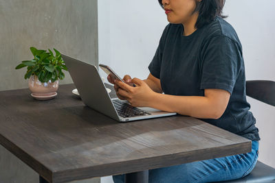 Midsection of man using mobile phone while sitting on table