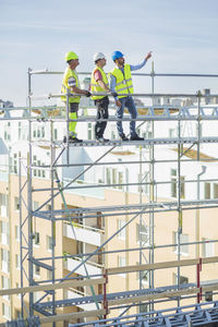 Architect explaining to colleagues while standing on scaffolding at site