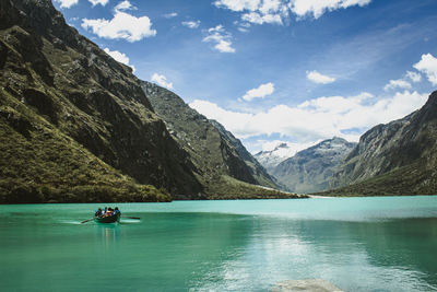 Scenic view of a boat in a lake sorrounded by mountains against sky