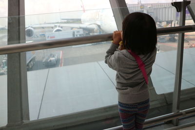 Rear view of girl standing by window