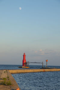 Lighthouse by sea against sky