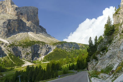 Road amidst trees and mountains against sky