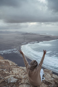 Rear view of man walking on shore by sea against sky