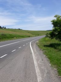 Empty road amidst landscape against sky