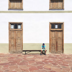 Man sitting on bench outside of building