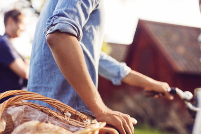 Midsection of man with bicycle at backyard