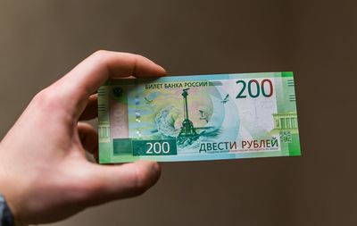 Close-up of man holding money against brown background