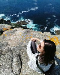 High angle view of woman sitting on rock formation against sea