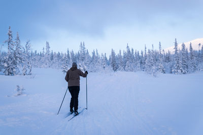 Rear view of man skiing on snow covered land