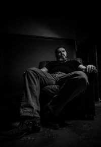 Low angle view of bearded man sitting on chair at home