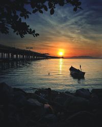 Silhouette boat in sea against sky during sunset