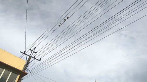 Low angle view of power cables against sky