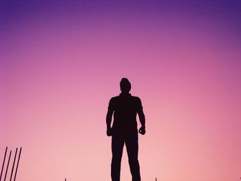 Silhouette man standing against dramatic sky during sunset