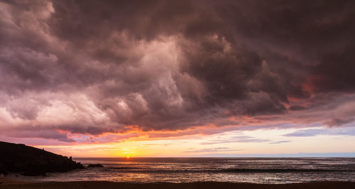 Scenic view of sea against dramatic sky during sunset