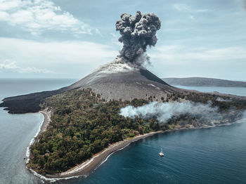 Volcano erupting on island against sky