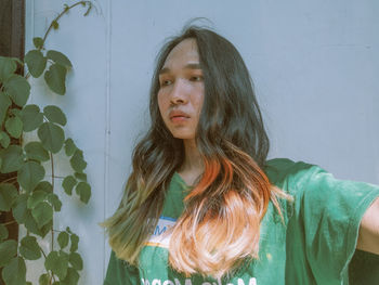 Portrait of young woman standing against wall