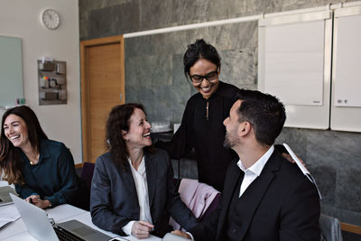 Smiling businesswoman interacting with cheerful colleagues in office