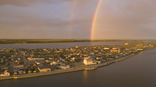 Aerial view of rainbow over buildings in city against sky