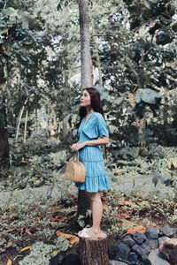 Full length of woman standing by tree in forest