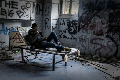 Man relaxing on bed in abandoned building