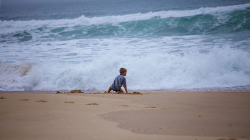 Kid plays on shore of huge, raging ocean. childhood freedom and adventure. discovery of the world