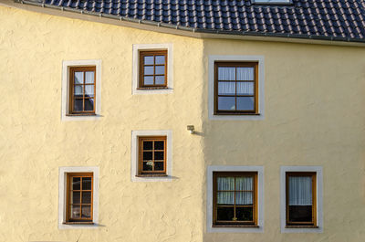 Yellow plaster facade with a bend and seemingly random placement of windows