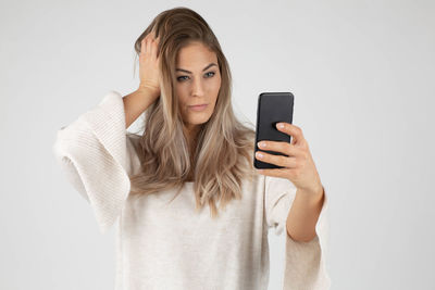 Portrait of young woman using smart phone against white background