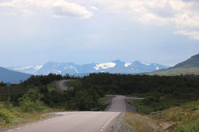 Road leading towards mountains against sky