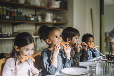 Multiracial children eating carrots for breakfast in day care center