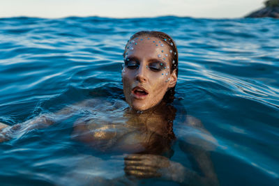 Young woman with golden skin in water