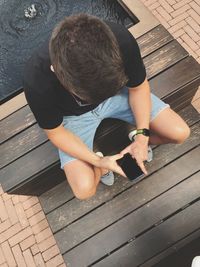 High angle view of man using mobile phone while sitting on steps