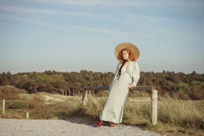 Rear view of woman standing on field against sky