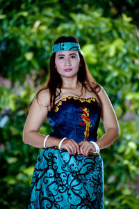 Portrait of young woman standing against plants