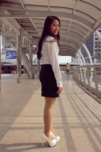 Portrait of smiling young woman standing on elevated walkway