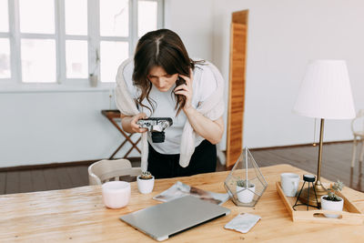 A young woman takes photos of objects goods things using a mobile phone creates content for a blog